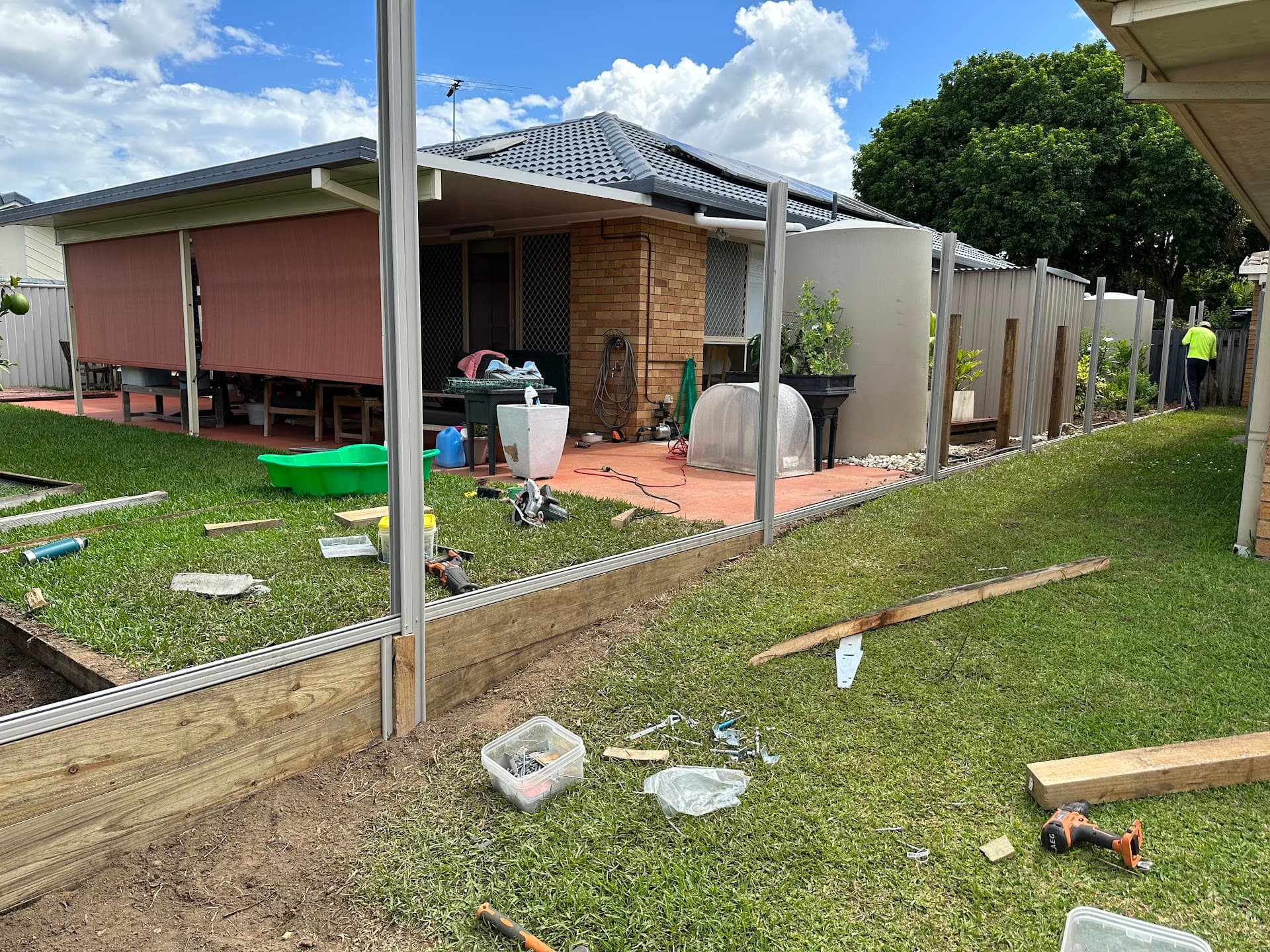 Timber retaining wall under construction in a backyard beside a patio