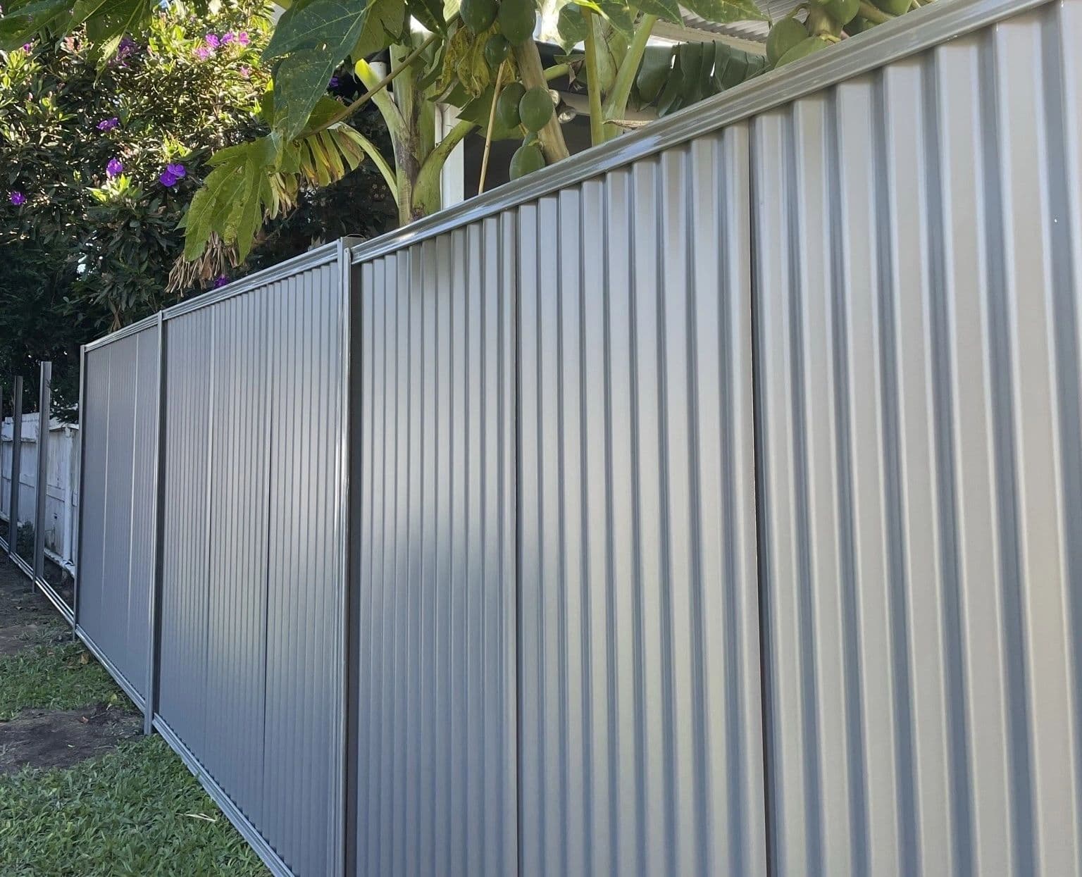Grey Colorbond boundary fence with a garden bed in front