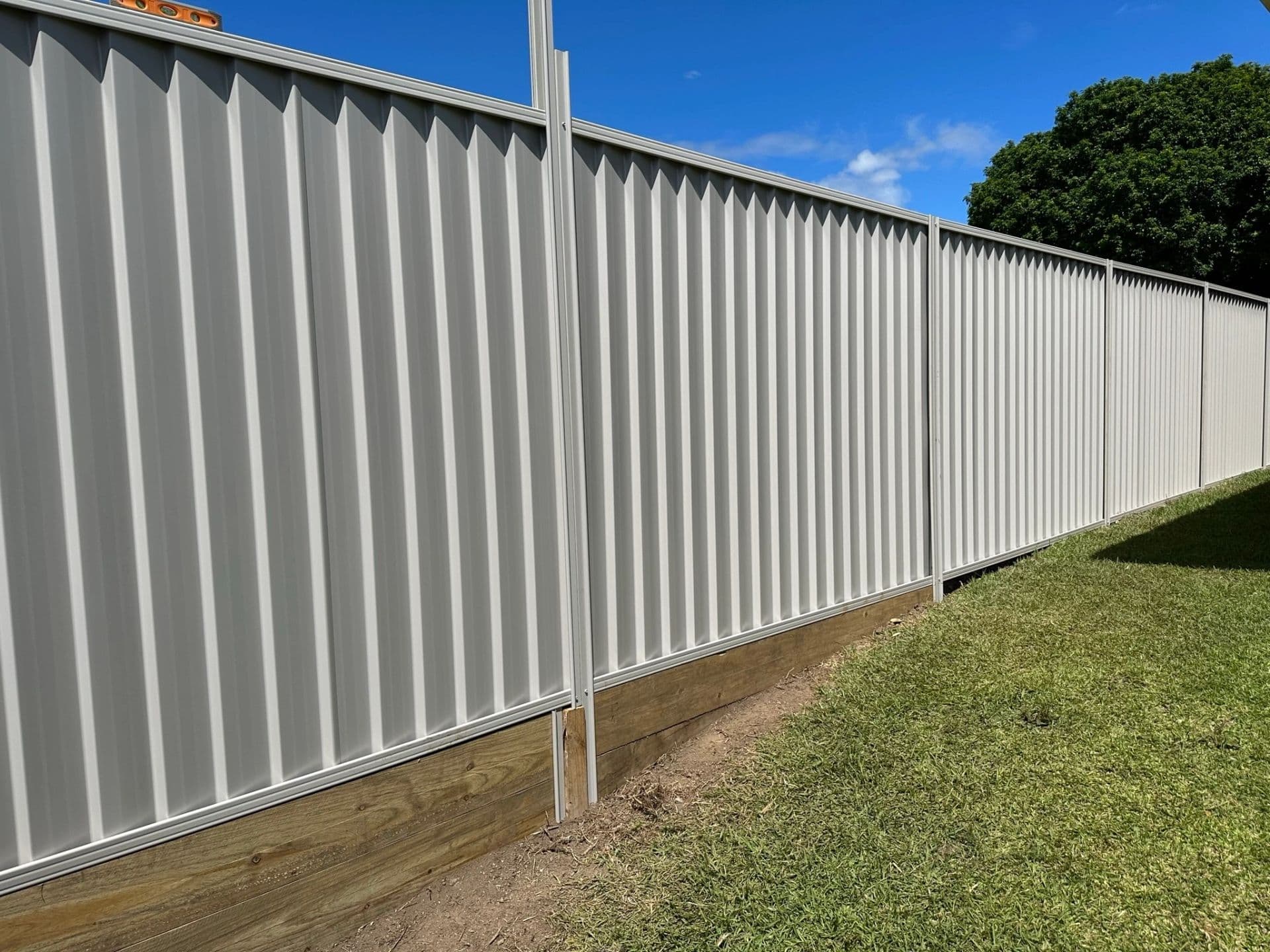 Grey Colorbond fence installed on top of a new concrete sleeper retaining wall