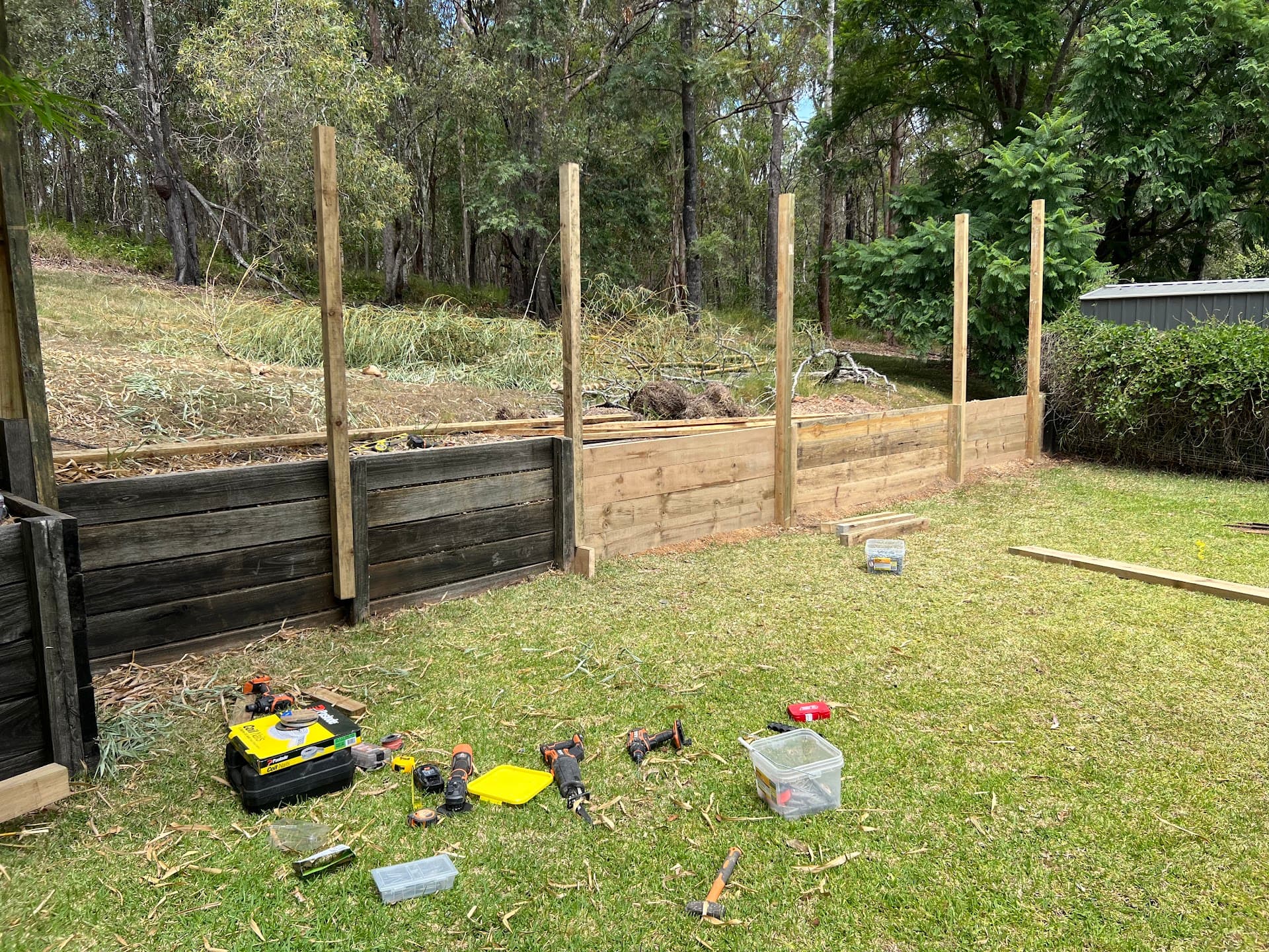 Timber sleeper retaining wall and fence posts being built on a sloping block